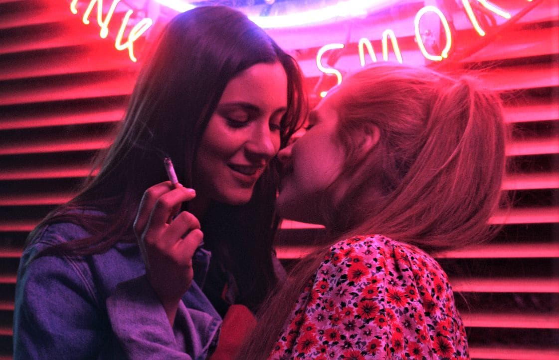 Extreme close up of two women, Natalia and Majka. Natalia is facing Majka; Majka is giving her back to Natalia.