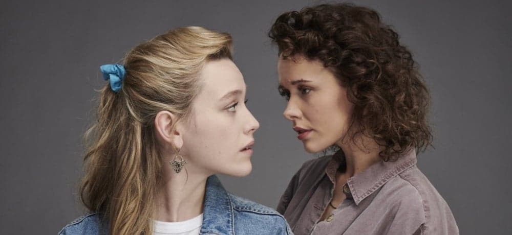 Dani and Jamie stand close and gaze into each other's eyes