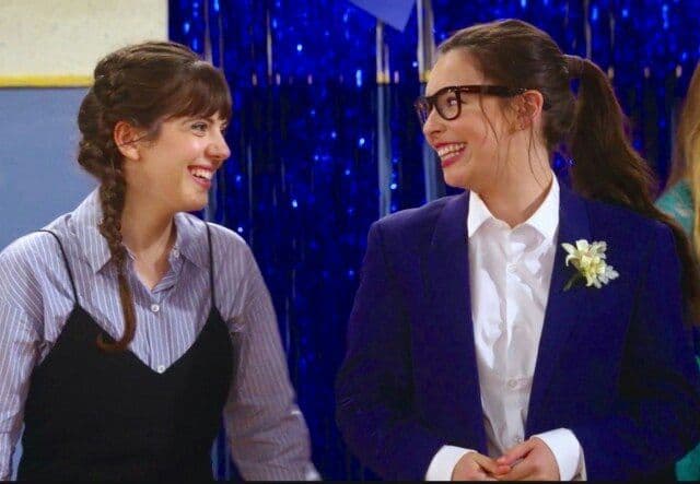 Syd and Elena smile at each other. Elena is in a suit.