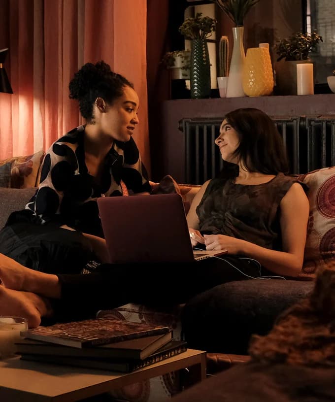 Kat and Adena talk to each other while they hang out on the couch.