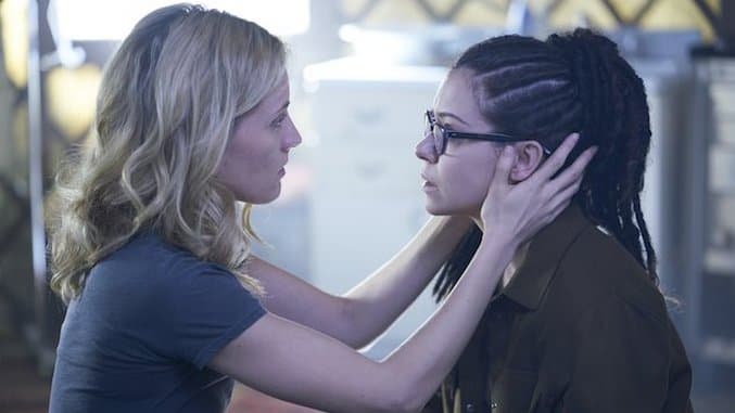 Delphine has both her hands on Cosima's head