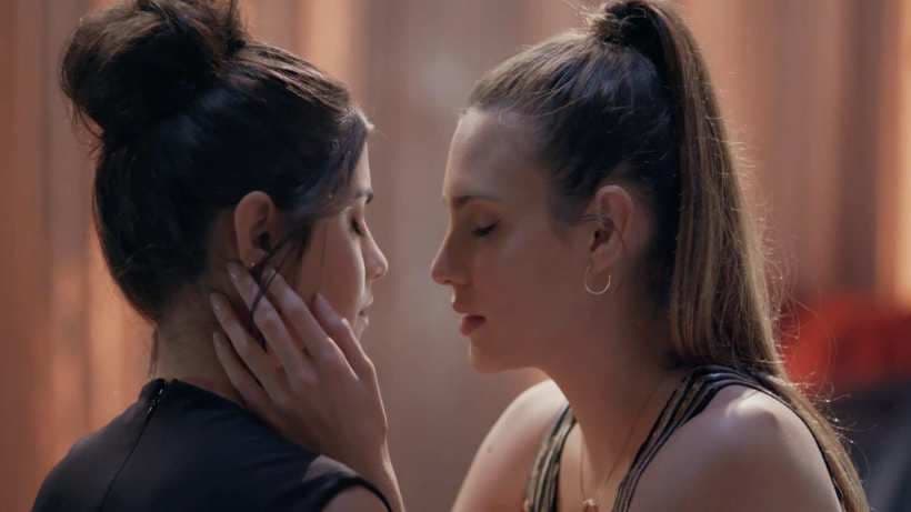 Juliana and Valentina are very close, almost kissing. They are both dressed elegantly.