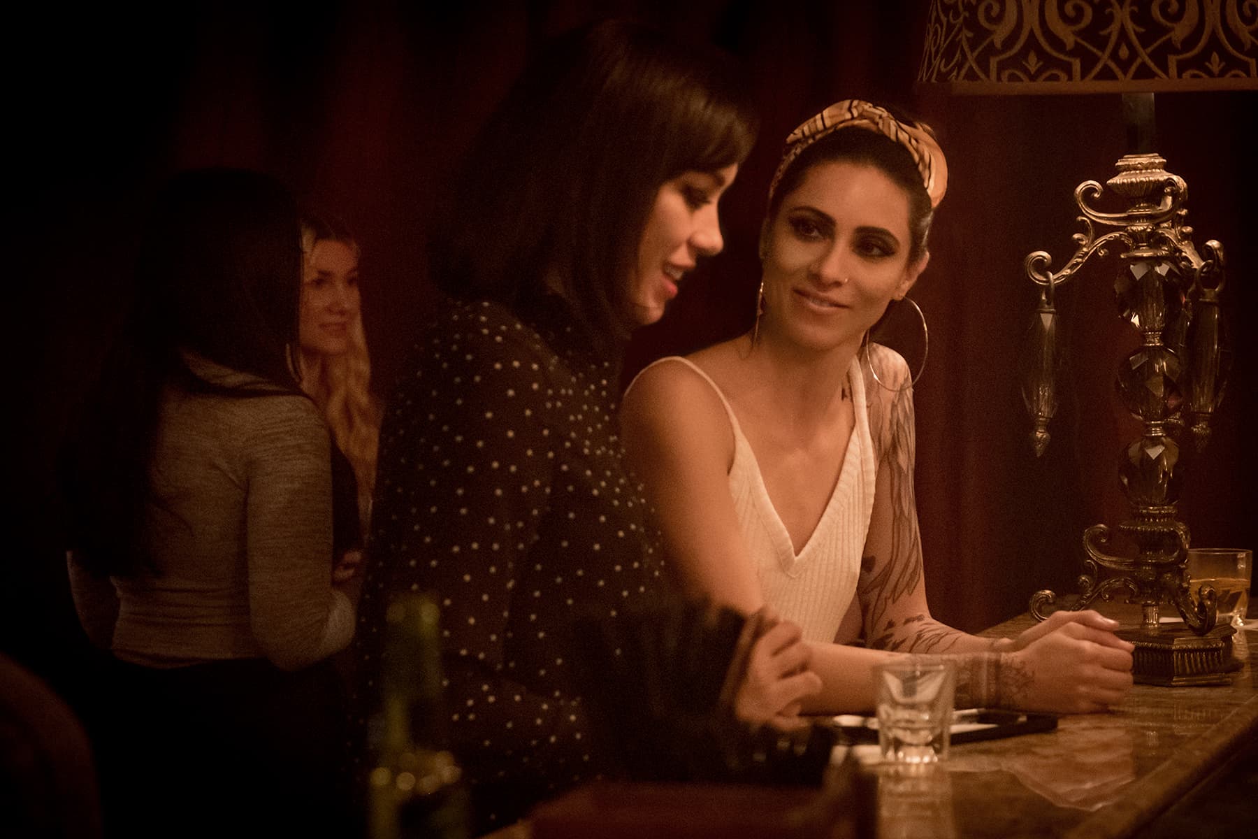 Two women are talking with each other at a bar